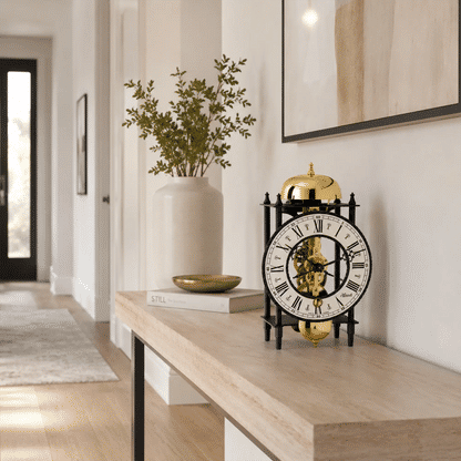 Reloj de mesa mecánico sobre consola de madera, esfera redonda con movimiento esqueleto dorado
