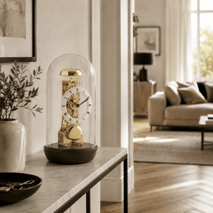 Reloj de mesa con cúpula de cristal y movimiento esqueleto visible, esfera dorada, base oscura