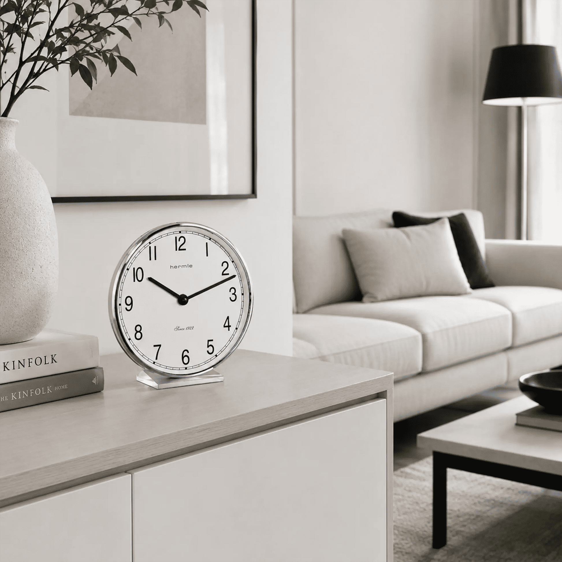 Reloj de mesa con esfera blanca, números negros y marco cromado sobre mueble