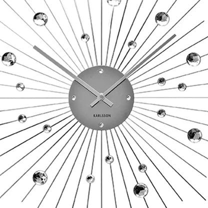 Nahaufnahme: Wanduhr-Uhrscheibe mit Karlsson-Schriftzug und Sonnenstrahlen aus Draht.