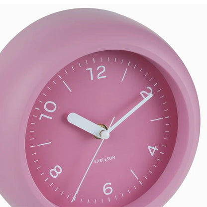 Nahaufnahme der rosafarbenen Wanduhr mit weißen Zeigern und 12-/6‑Anzeige