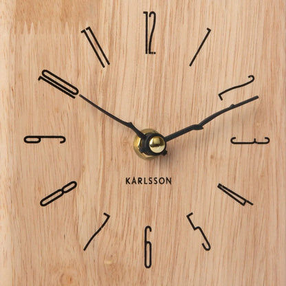 Nahaufnahme Zifferblatt der Wanduhr aus hellem Holz mit schwarzen Zeigern und goldfarbenem Zentrum