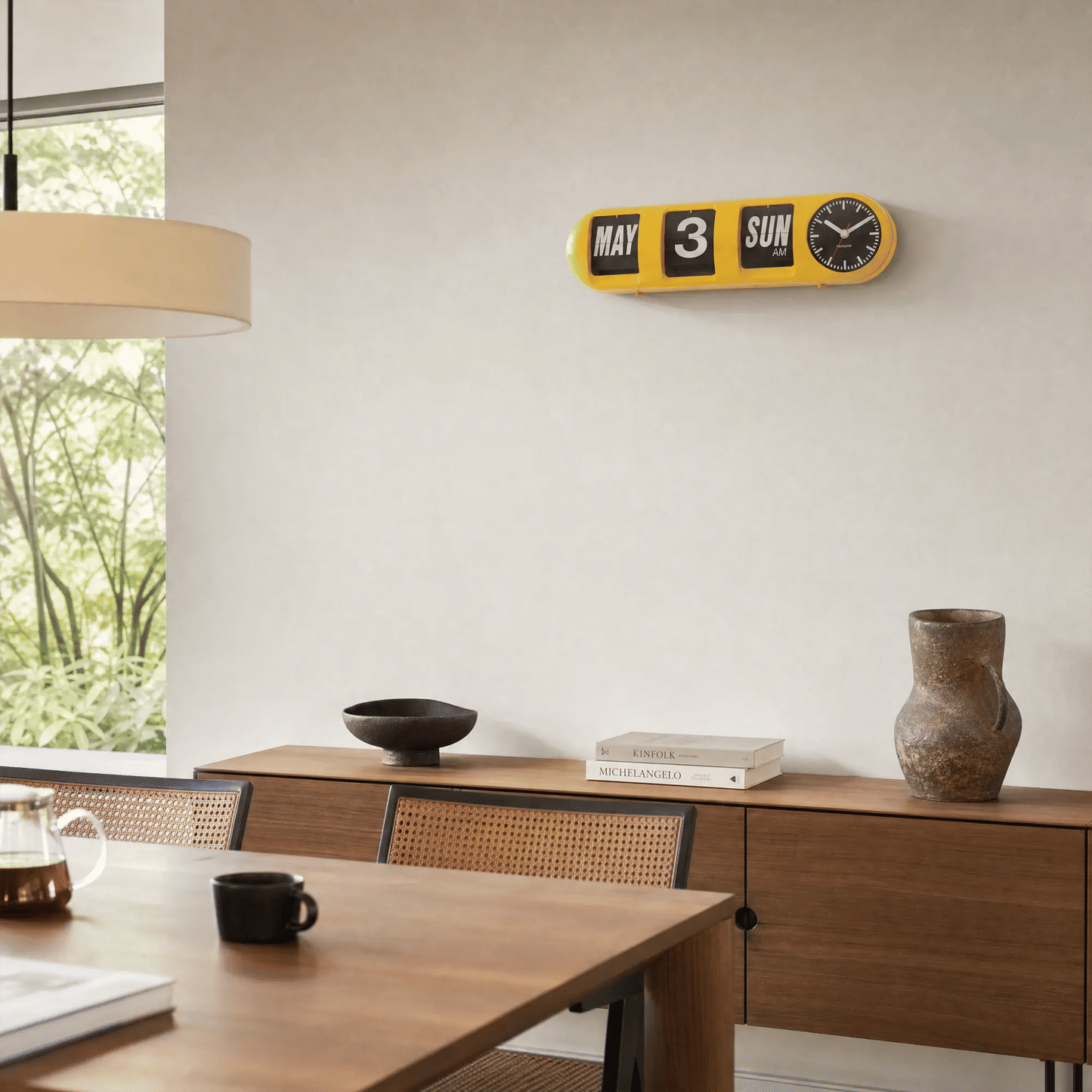 Leuchtgelbe Tube-Flip-Wanduhr an der Wand mit Klappzahlen und rundem Uhrwerk