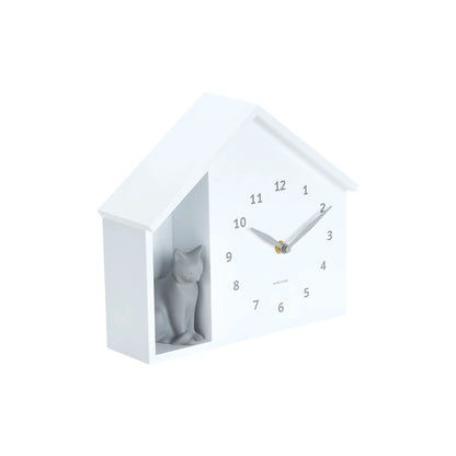 Weiße Haus-Wanduhr mit Katze im Fenster, analoge Zeiger und Ziffern 1–12