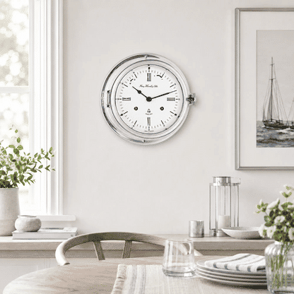 "Reloj analógico redondo con marco plateado y esfera blanca, manecillas azules"