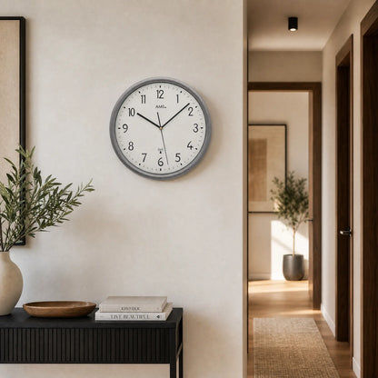 Reloj de pared inalámbrico con marco gris y esfera blanca, manecillas negras y marcas de minutos en puntos