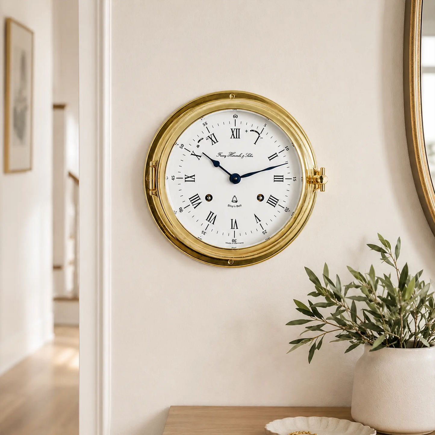 Reloj de pared redondo con anillo de latón y esfera blanca, manecillas azules y números romanos.