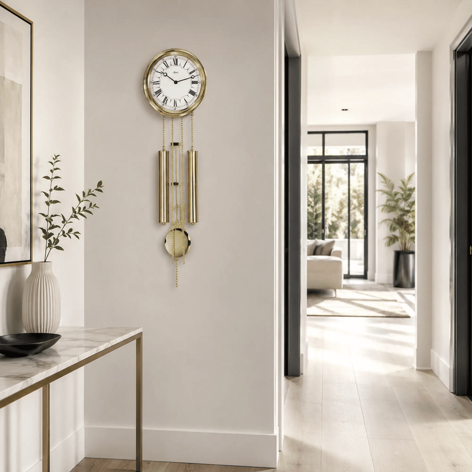 Reloj de pared redondo de latón con esfera y péndulo dorados sobre pared blanca