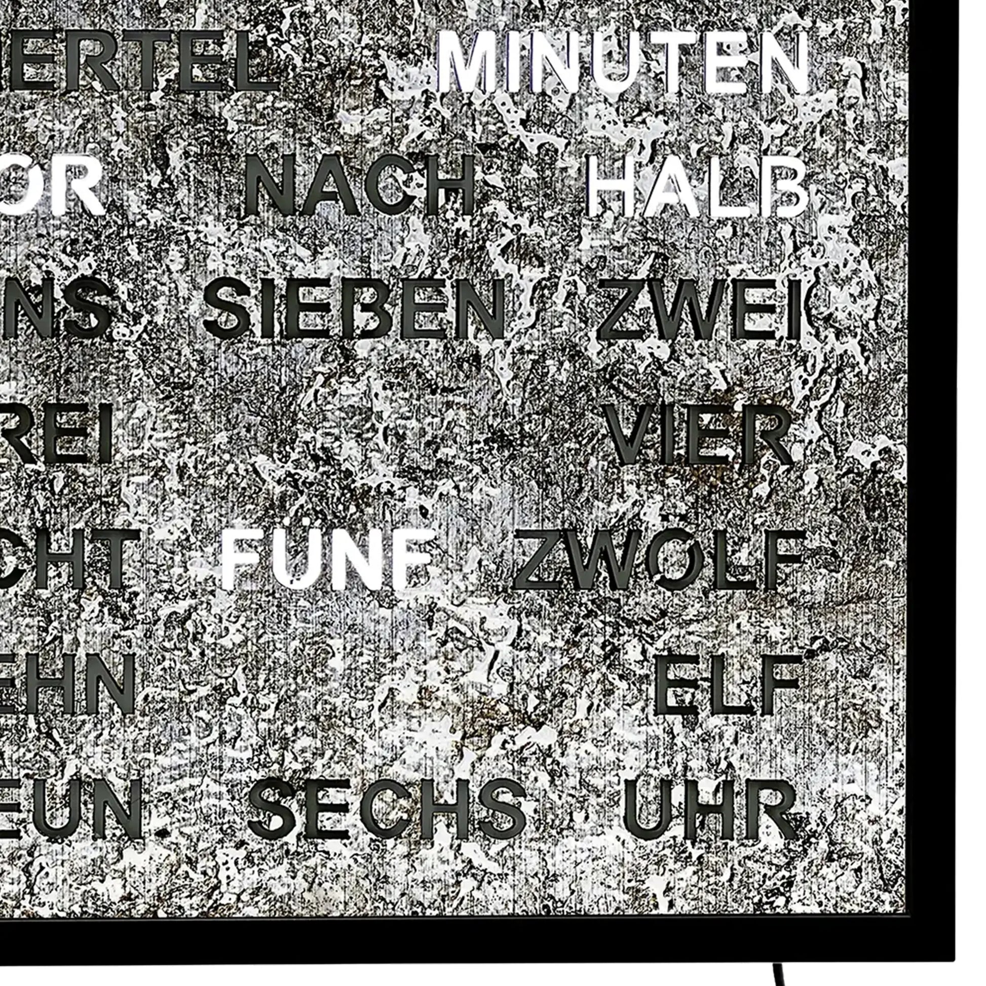 Wanduhr mit schwarzem Metallrahmen und LED-Zeitanzeige, beschriftete Metalloberfläche.