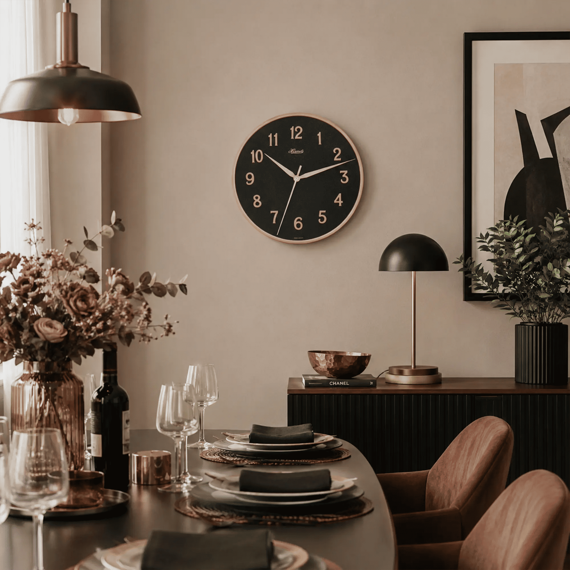 "Reloj de pared con esfera negra, bisel de oro rosa y números romanos"