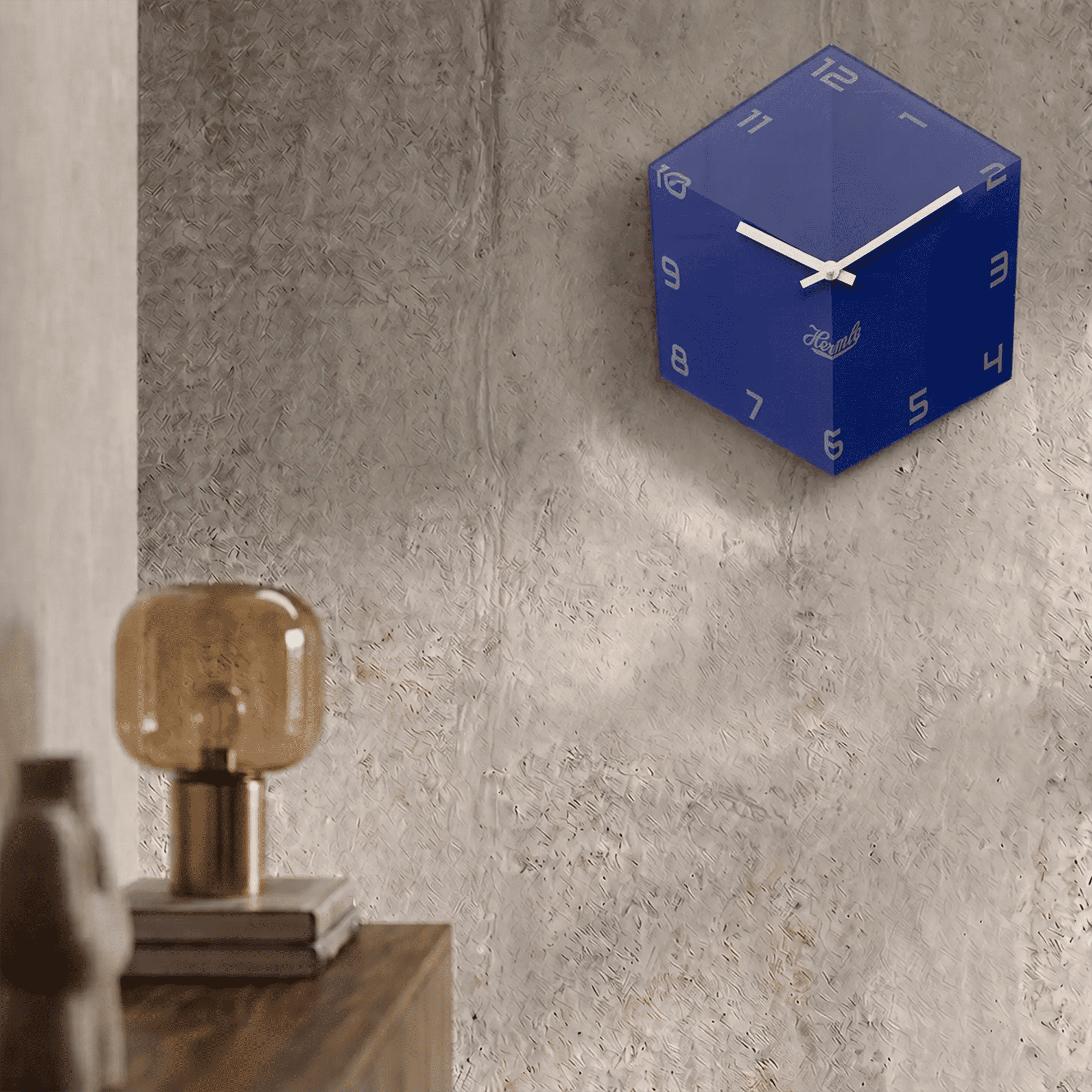 Reloj de pared en caja cúbica azul con números y manecillas blancos en la pared