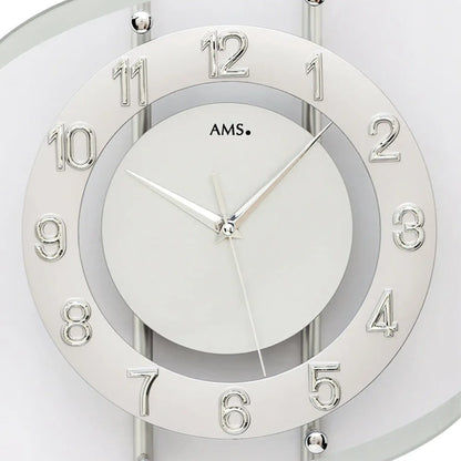 Nahaufnahme: Silberne Funk-Wanduhr mit rundem Ziffernblatt, römischen Zahlen und Zeigern.