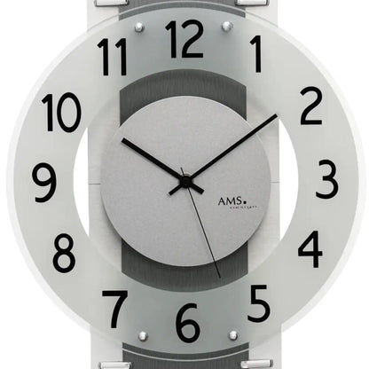 Nahaufnahme Wanduhr: graues Ziffernblatt, schwarze Zeiger, AMS-Logo