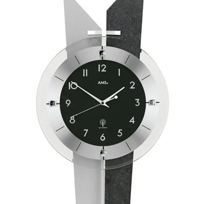 Nahaufnahme Zifferblatt: Wanduhr mit AMS-Logo, schwarzen Segmenten und silbernen Zeigern