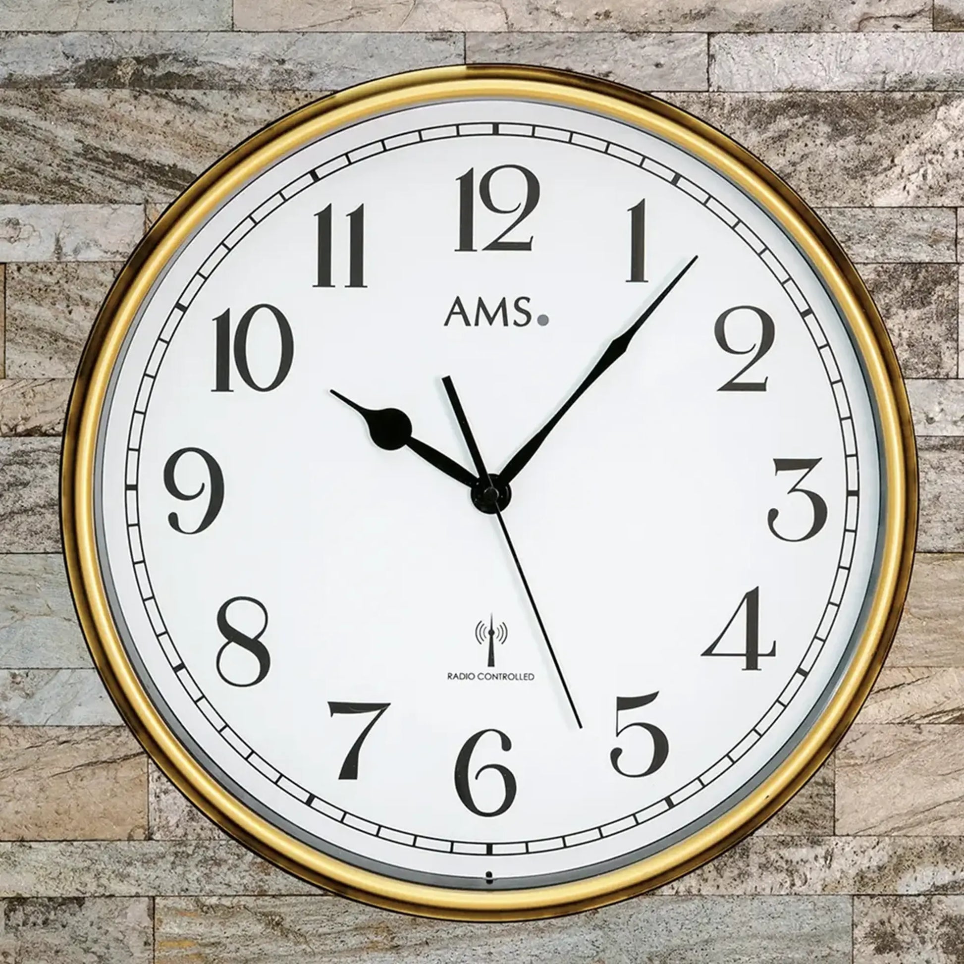 Nahaufnahme Wanduhr: brauner Rahmen, weiße Skala, Funkgesteuert-Text, AMS, Mineralglas