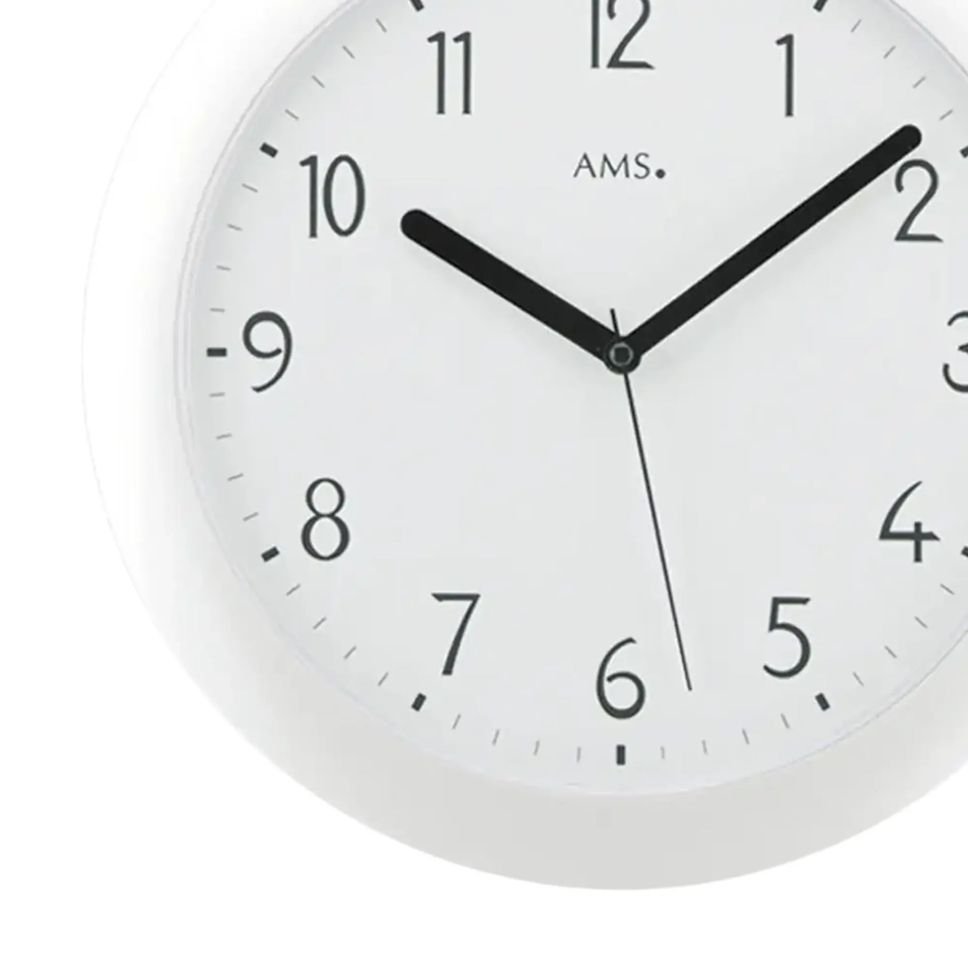 Nahaufnahme einer weißen Wanduhr mit schwarzen Zeigern und AMS-Markierung im Zifferblatt.