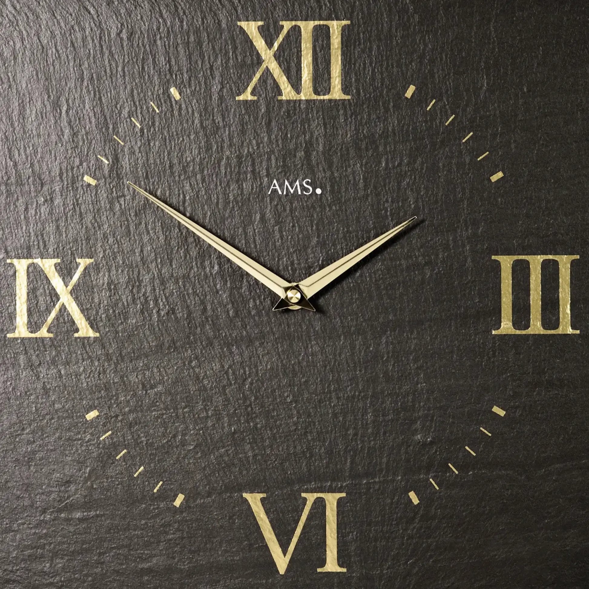 Nahansicht Wanduhr: dunkles Schieferblatt, goldene römische Ziffern und Minutenzeiger