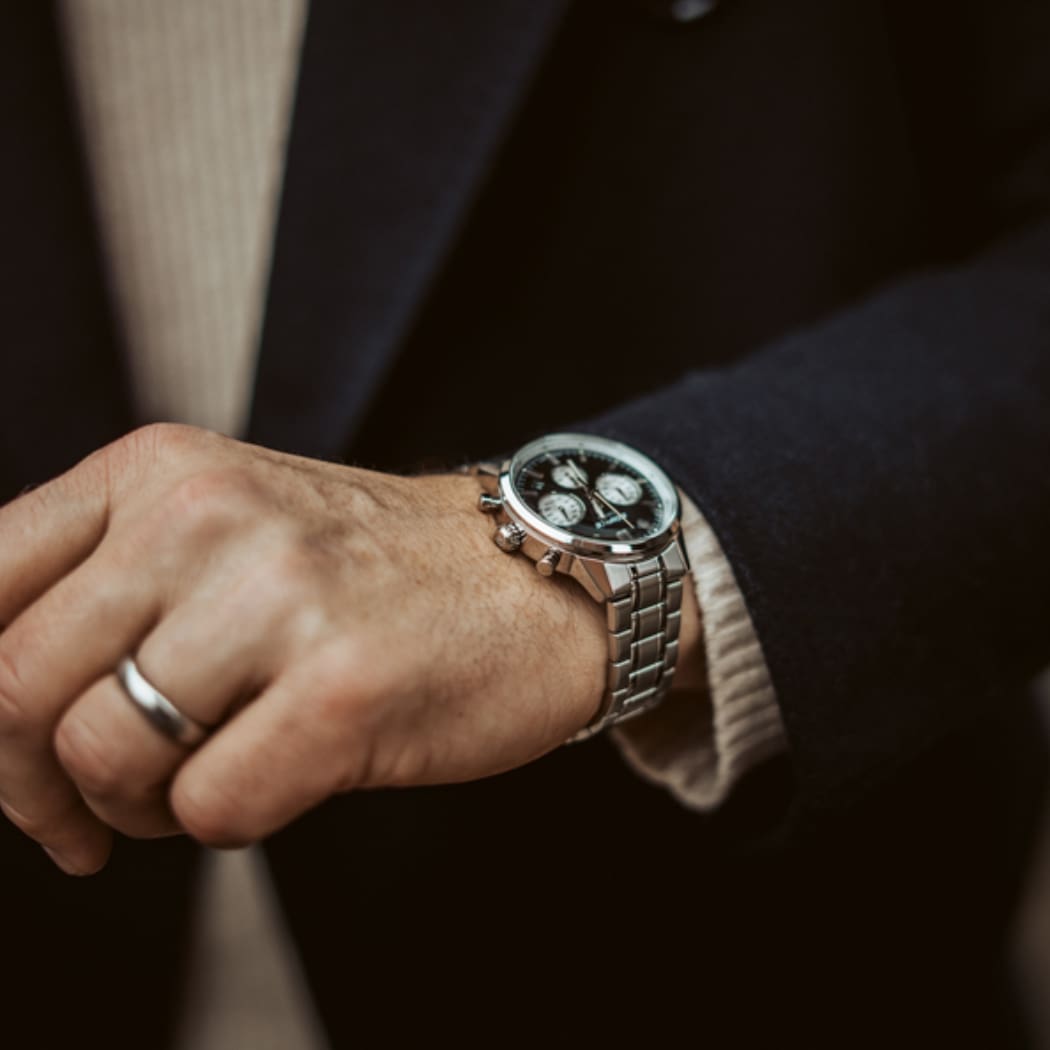 Herrenarmbanduhr am Handgelenk mit schwarzem Zifferblatt und Edelstahlband