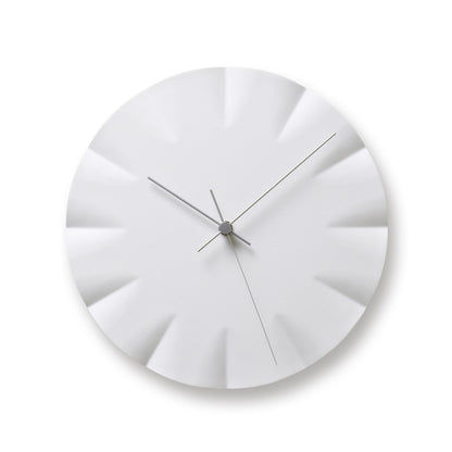 Runde Wanduhr in Weiß mit gerippten Segmenten am Zifferblatt und schlanken Zeigern