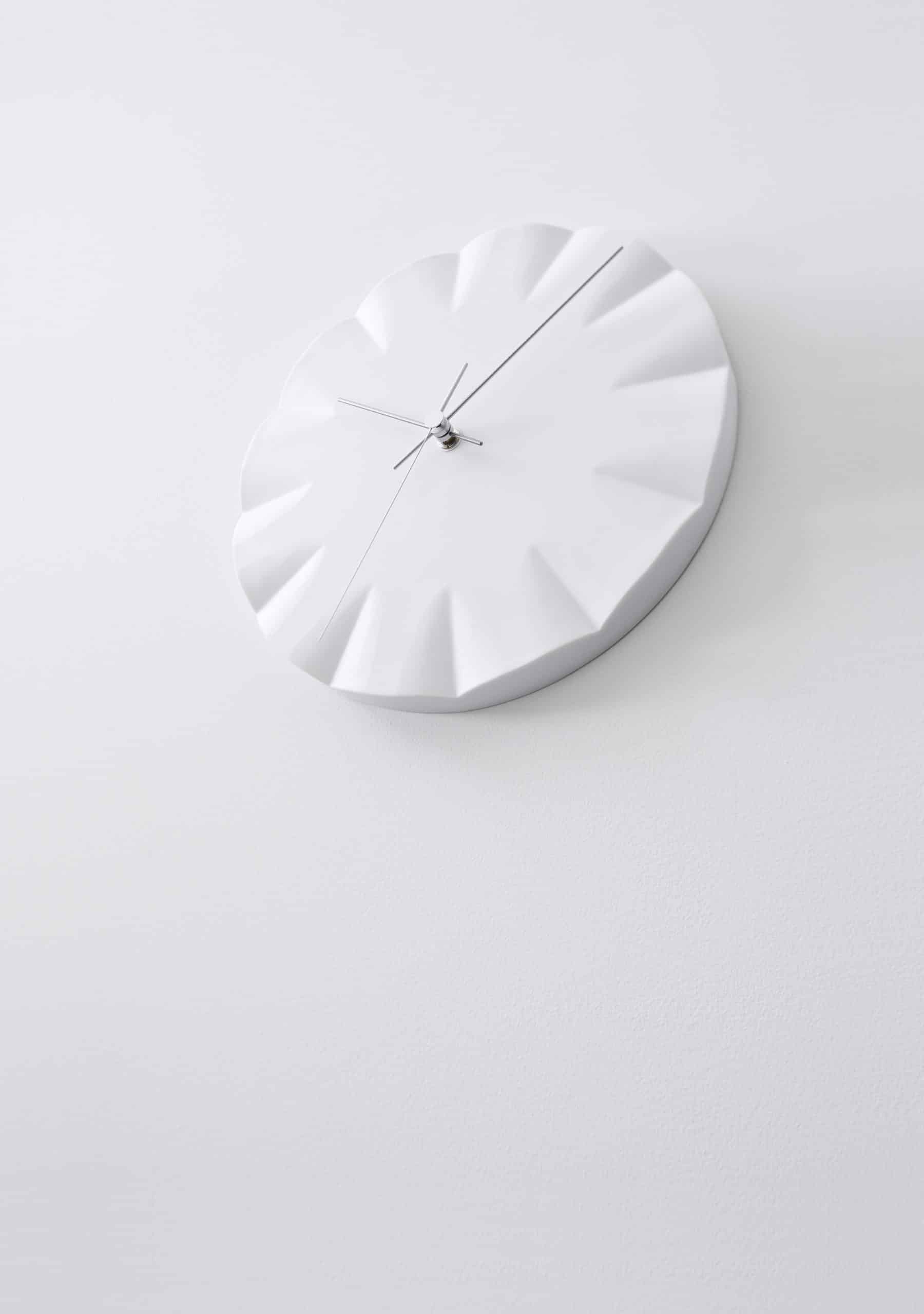 Runde Wanduhr in Weiß mit Relief-Zifferblatt, drei schlanken Zeigern und Mittelachse
