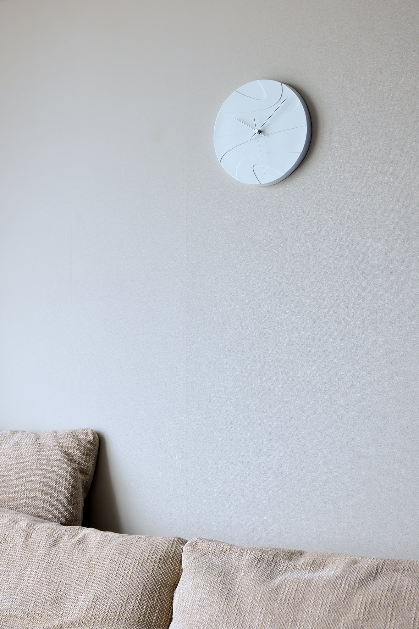 Weiße Porzellan-Wanduhr an der Wand mit schmalen Linien und Uhrzeigern