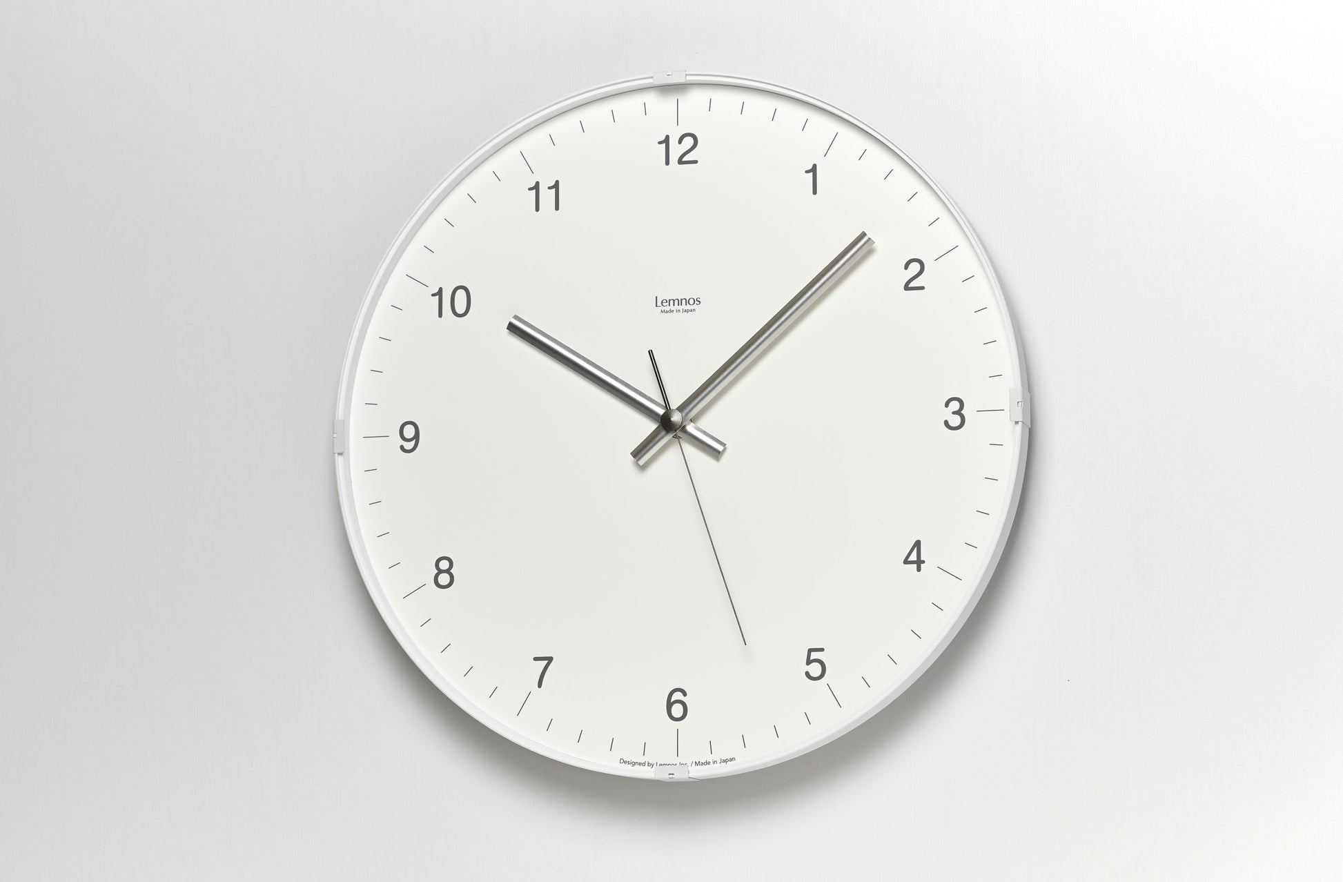 Runde Wanduhr mit weißem Zifferblatt, Zahlen 12–6 und drei Zeigern