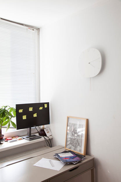 Weiße runde Wanduhr an der Wand, seitlich im Raum gezeigt