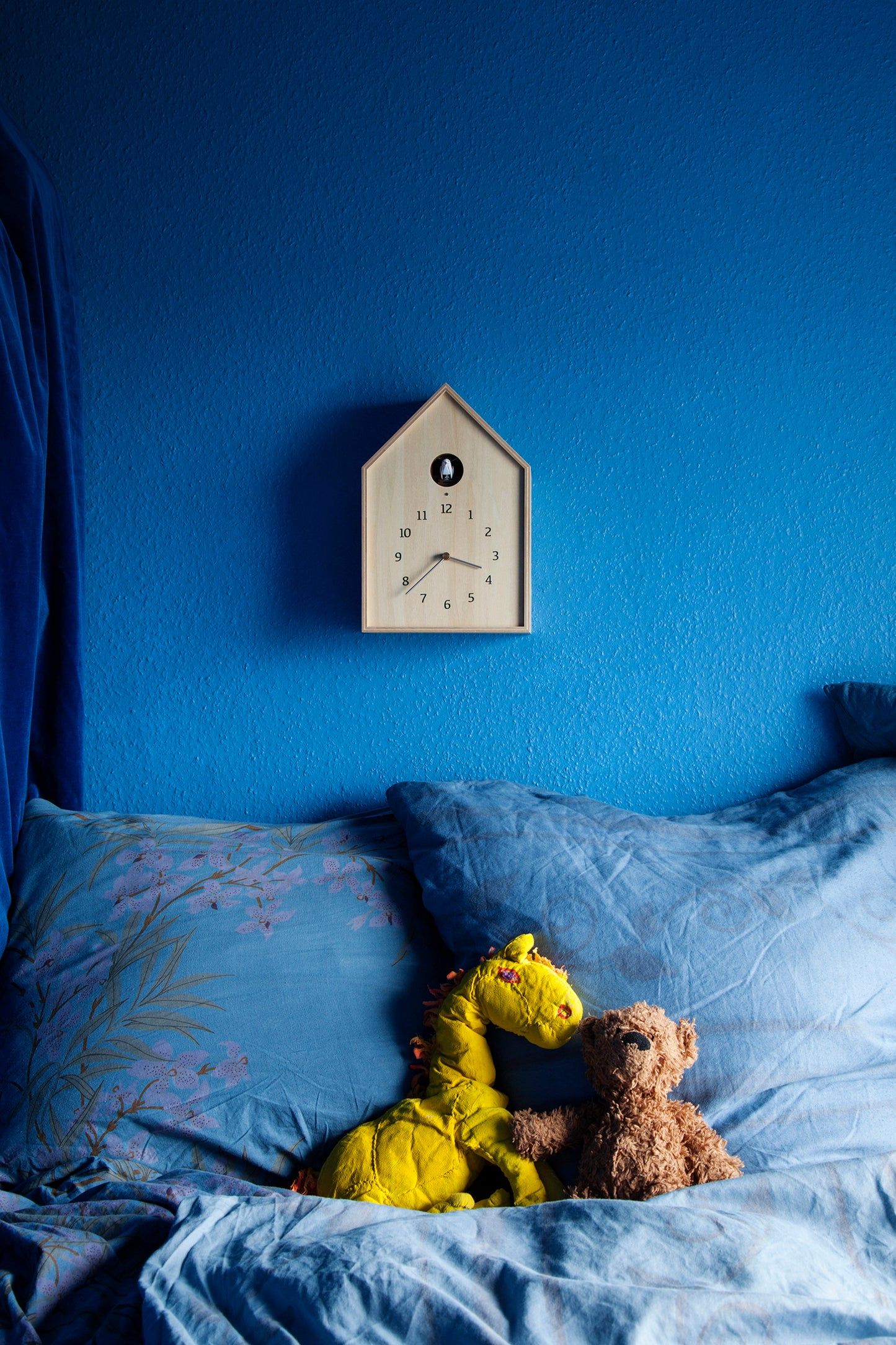 Vogelhaus-Wanduhr an der Wand, weißes Gehäuse mit schwarzem Rundfenster und Ziffern