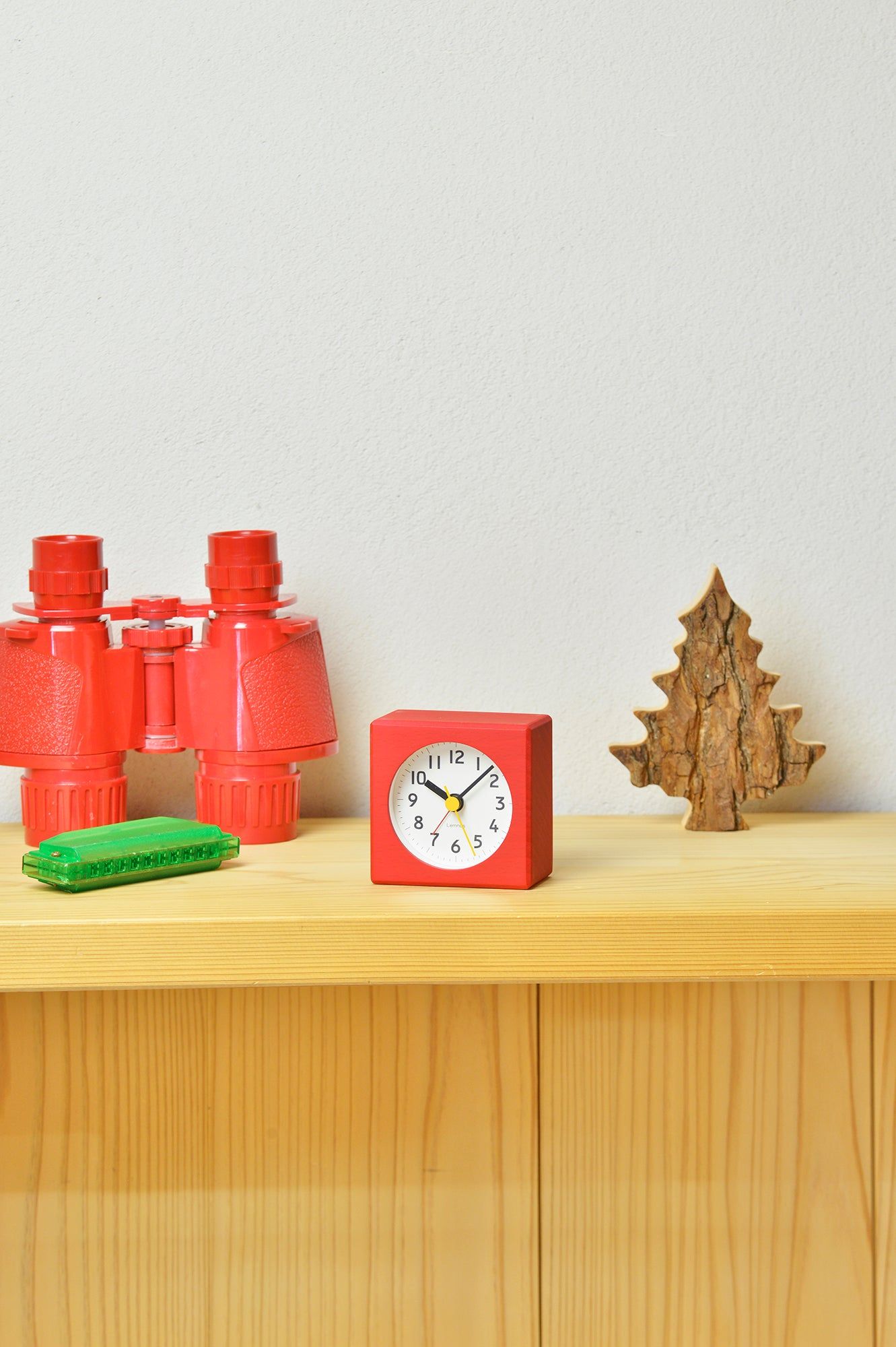 Roter Tischwecker auf Holzregal mit weißem Zifferblatt und goldenen Zeigern