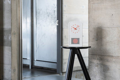 Weiße Wanduhr auf Stativ, gepunktetes Ziffernblatt mit kleinem rotem Muster