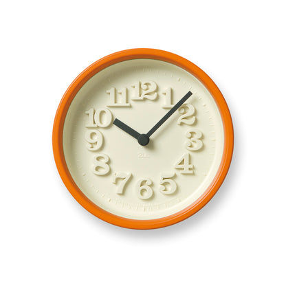 Runde Wanduhr mit orangem Rahmen, beigem Zifferblatt und schwarzen Zeigern