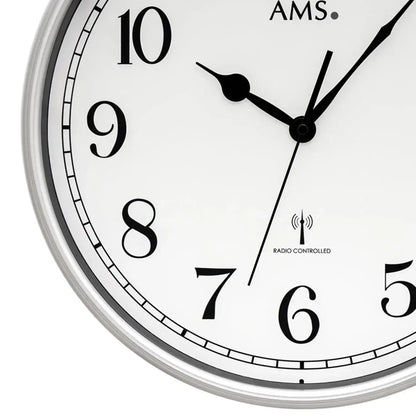 Runde Funk-Wanduhr mit silbernem Rand, schwarzem Ziffernblatt, schwarzen Zeigern und AMS-Logo