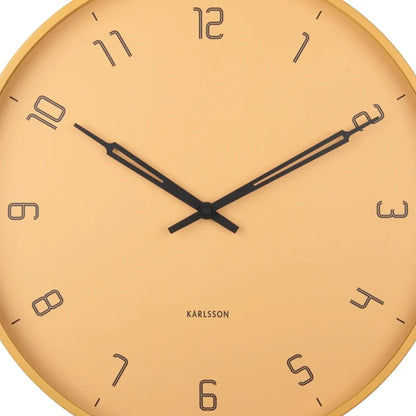 Nahaufnahme Wanduhr: honiggelbes Zifferblatt, schwarze Zeiger, arabische Zahlen