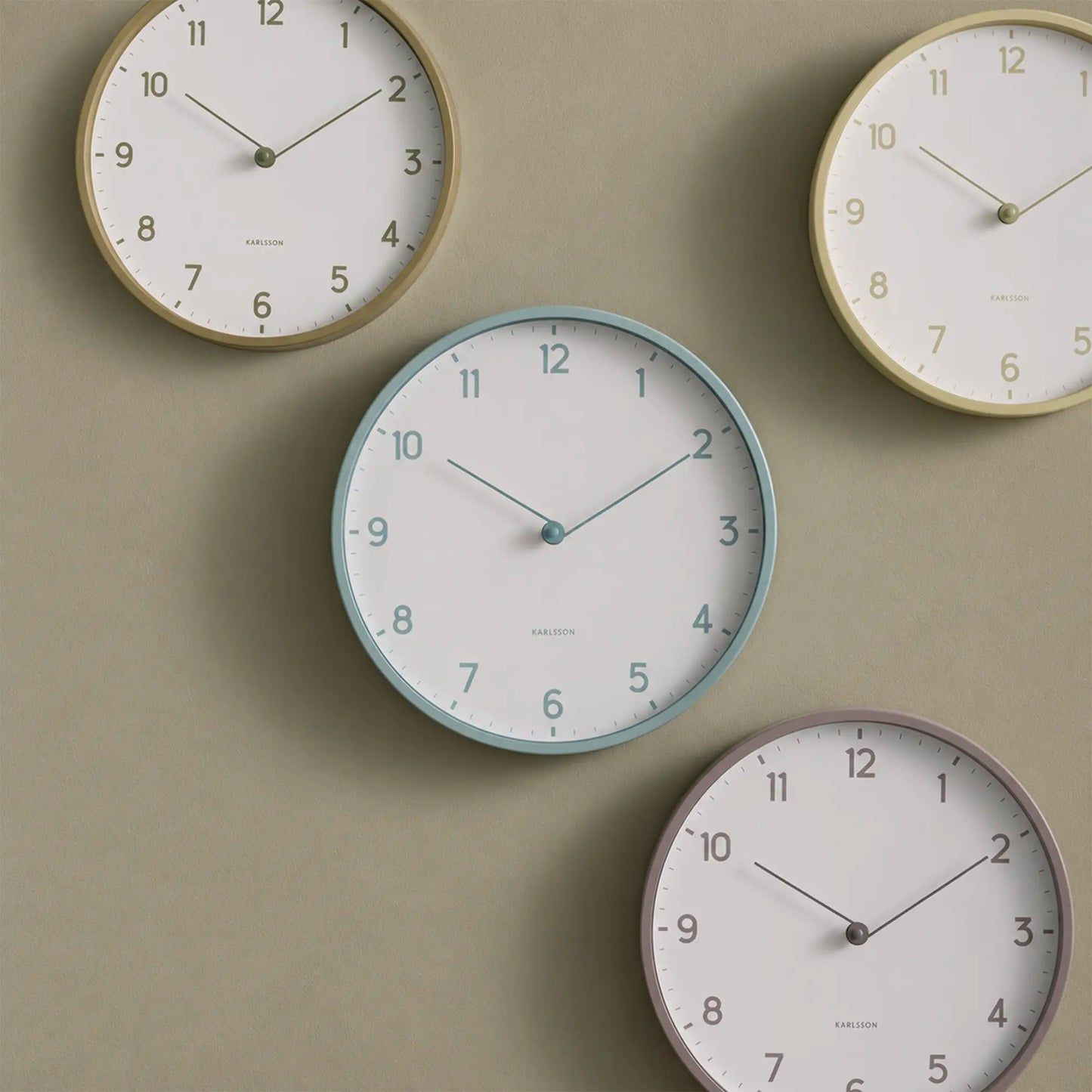 Hellblaue Karlsson Wanduhr mit beigem Rahmen, arabischen Ziffern und schlanken Zeigern