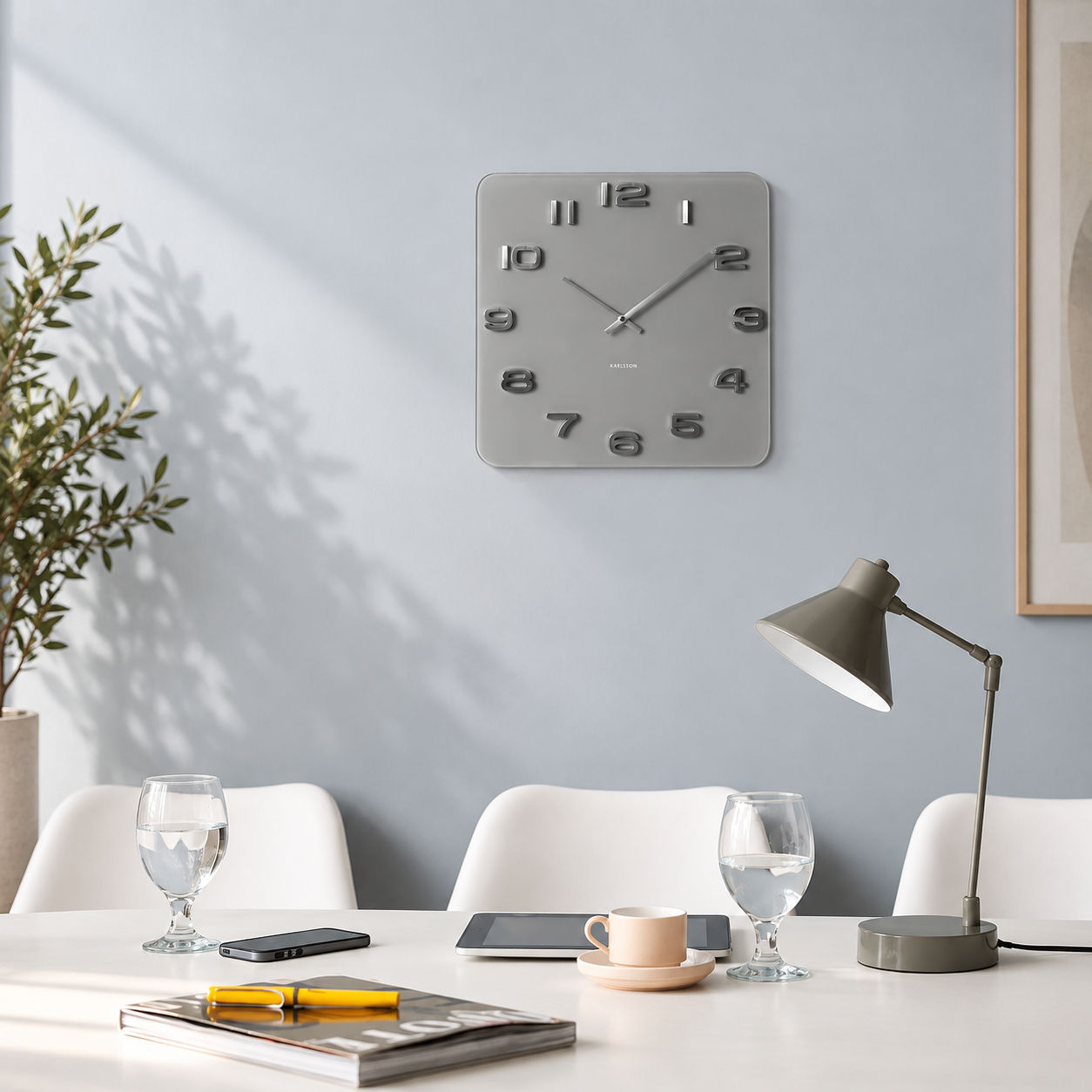 Quadratische graue Wanduhr mit offenem Zifferblatt, Metallzeigern und Ziffern im Relief
