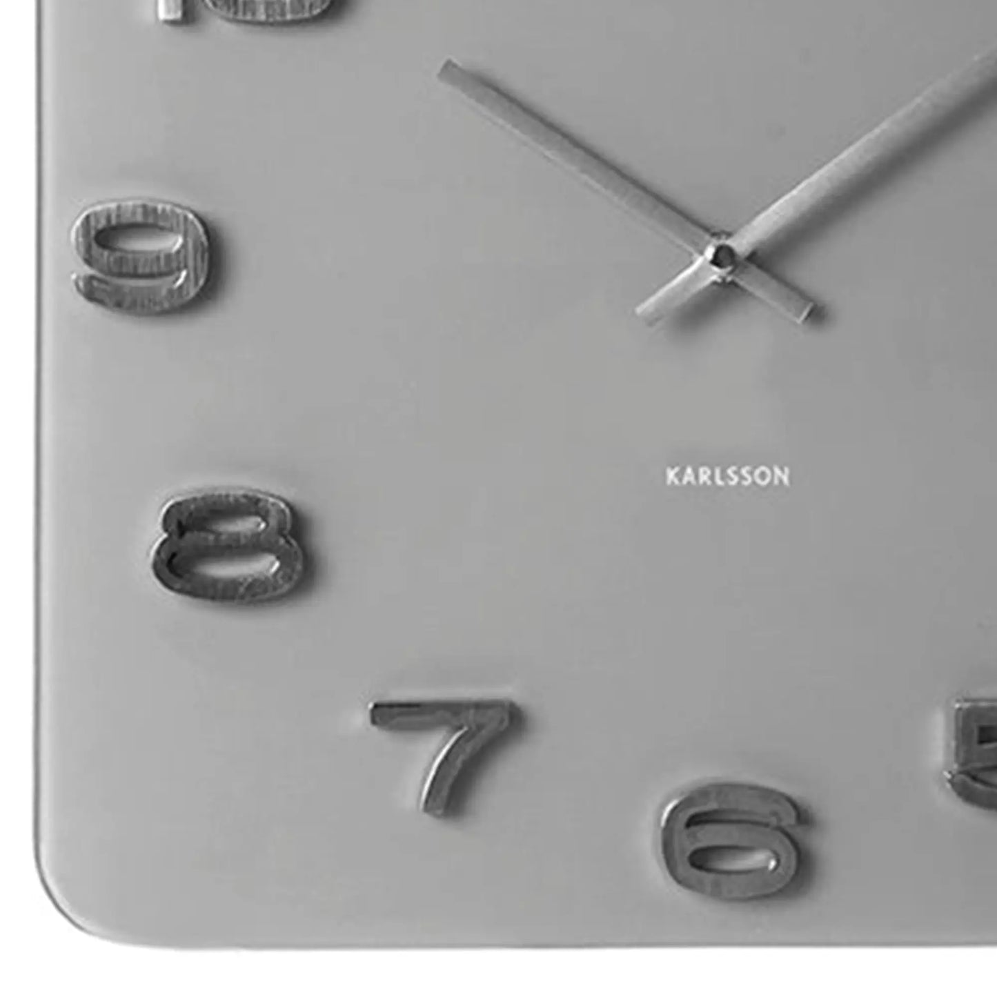Nahaufnahme: graue Wanduhr mit offenen Zahlen und „KARLSSON“ Schriftzug im Gehäuse