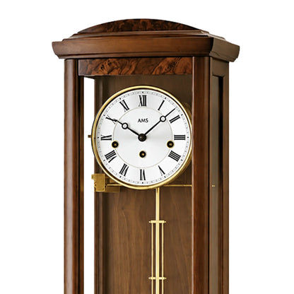 Nahaufnahme der Wanduhr: rundes Zifferblatt mit römischen Zahlen und Pendelmechanik (AMS).