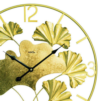 Nahaufnahme Wanduhr: goldfarbenes Blattmotiv, schwarze Zeiger, arabische Ziffern auf Rahmen