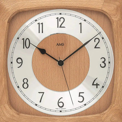 Nahansicht: Wanduhr-Zifferblatt mit AMS-Schrift im Holz-Zentrum, schwarzen Zeigern und Zahlenring