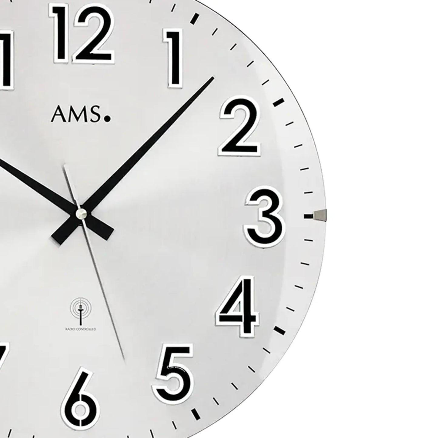 Detail der silbernen Wanduhr: weißes Zifferblatt, schwarze Zeiger, Zahlen 1–6, AMS