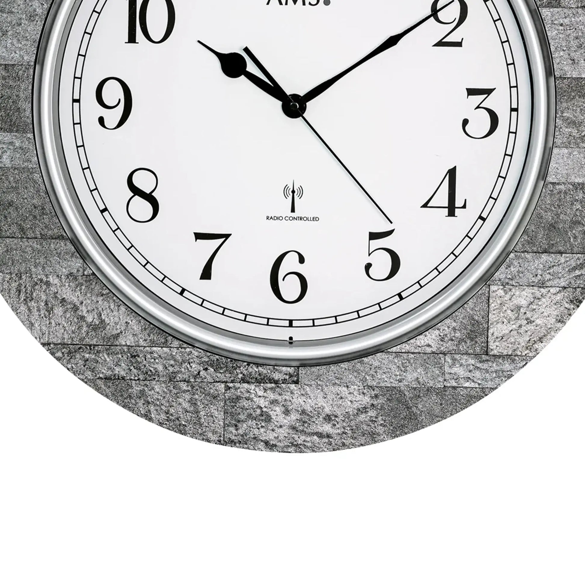 Nahaufnahme Wanduhr: weißes Ziffernblatt, schwarze Zeiger, „RADIO CONTROLLED“-Logo.