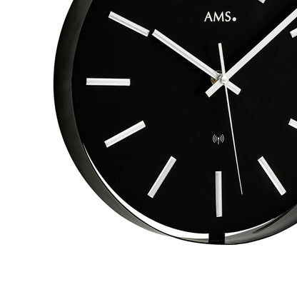 Nahansicht AMS Funk-Wanduhr: schwarzes Zifferblatt, silberne Zeiger und Funk-Symbol