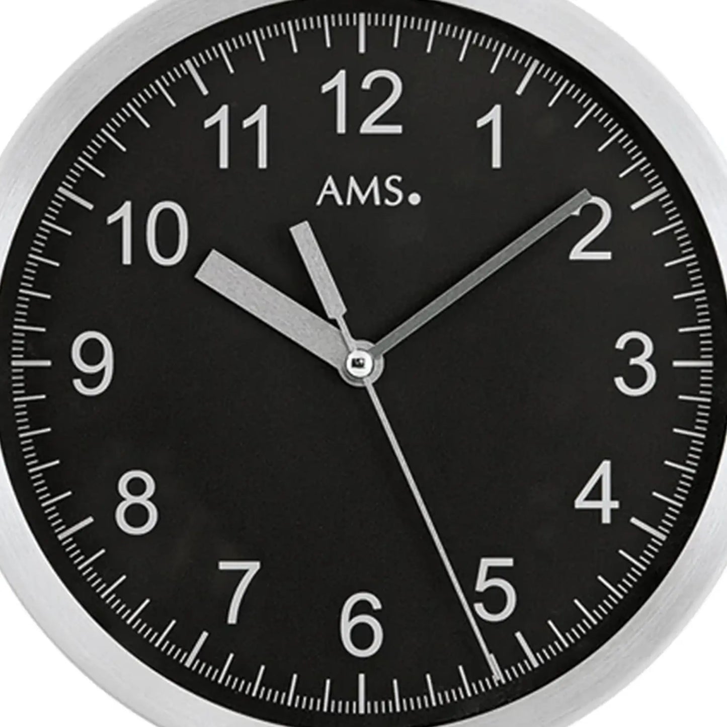 Nahaufnahme Wanduhr mit schwarzem Ziffernblatt, AMS-Schriftzug und Aluminiumrahmen
