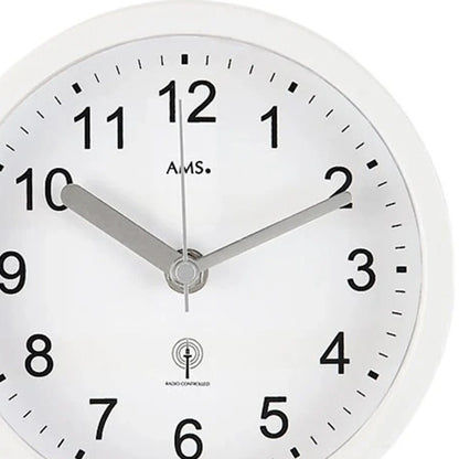 Nahaufnahme: weiße runde AMS Wanduhr mit schwarzen Ziffern, Zeigern und Logo