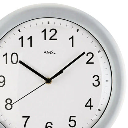 Nahaufnahme der Wanduhr: weißes Zifferblatt, schwarze Zahlen, schwarze Zeiger, silberner Rand