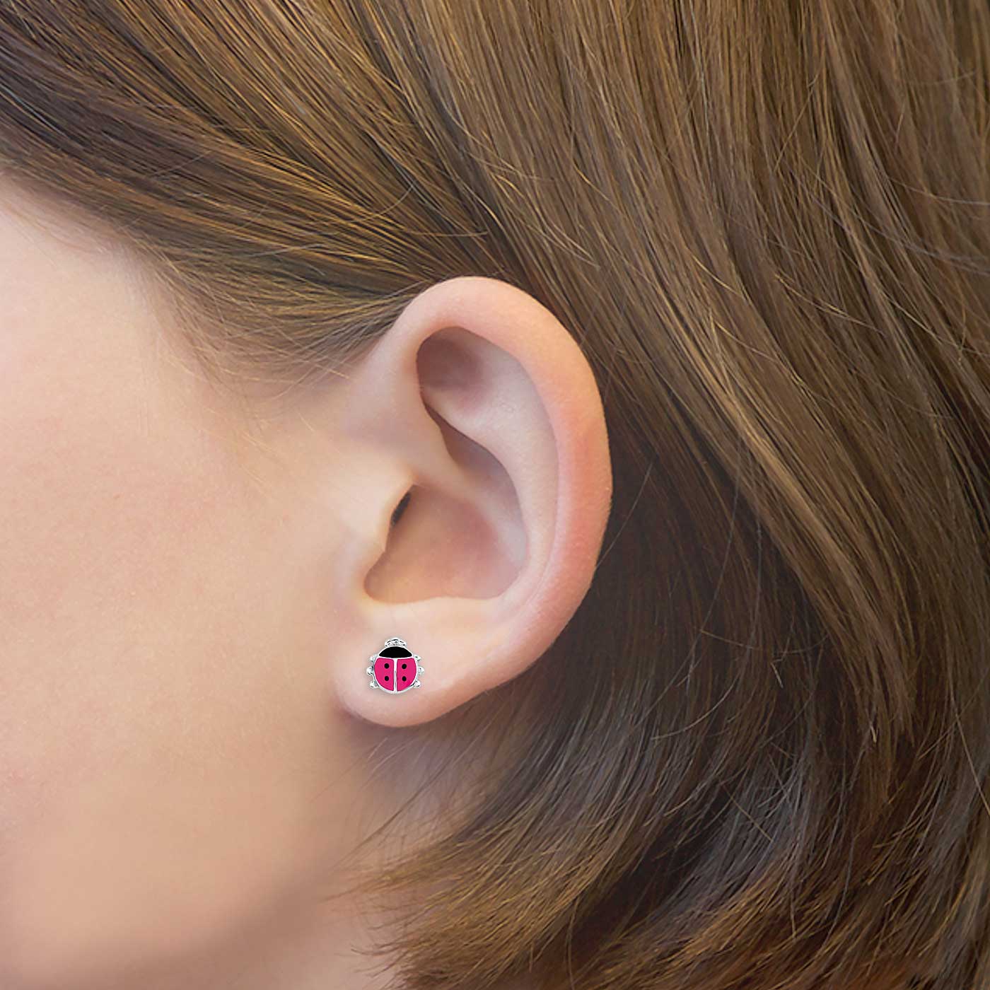 Rosa Marienkäfer-Ohrstecker am Ohr, silberner Rand, schwarze Punkte