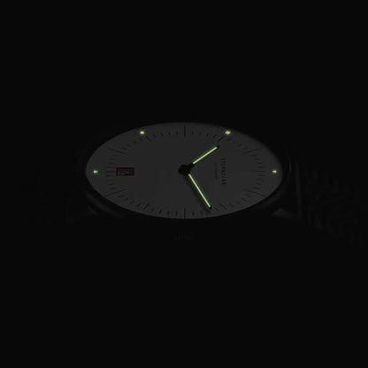 Herrenuhr mit dunklem Zifferblatt, grün leuchtenden Markierungen und Zeigern