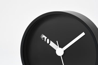 Schwarze Wanduhr im Nahblick: Ziffernfeld, Zeiger und 40-Markierung