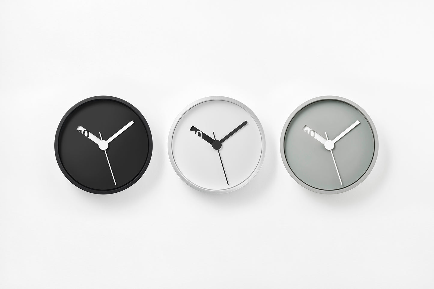 Drei runde Wanduhr-Varianten: schwarze, weiße und graue Zifferblätter mit schwarzen Zeigern.