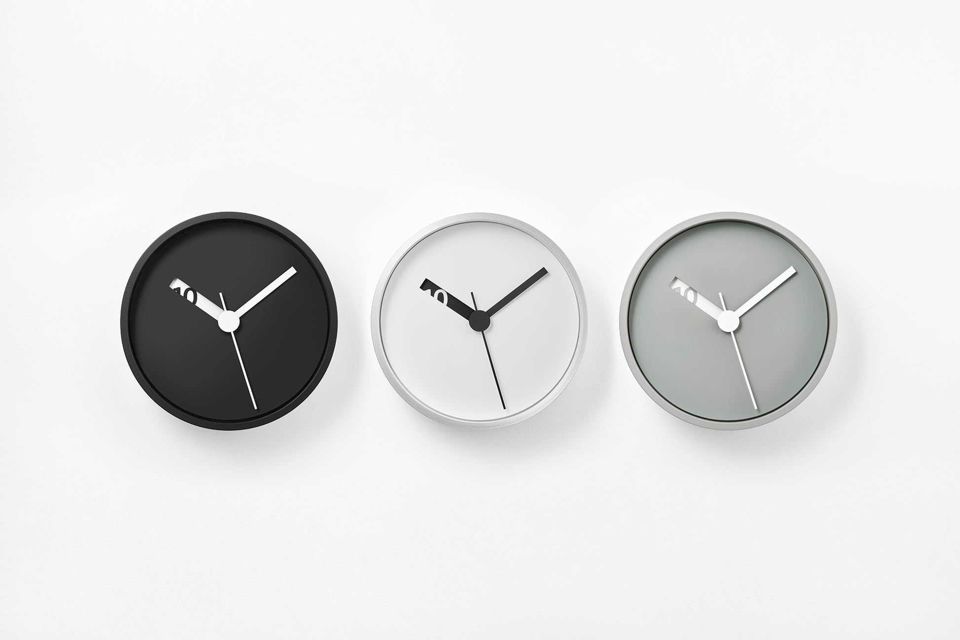Drei runde Wanduhr-Varianten: schwarze, weiße und graue Zifferblätter mit schwarzen Zeigern.